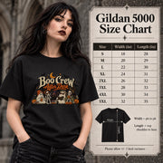 Size chart for Gildan 5000 unisex T-shirt featuring a “Boo Crew After Dark” Halloween design with ghosts, skeletons, pumpkins, books, bats, drinks, and a crescent moon in retro orange and cream tones.