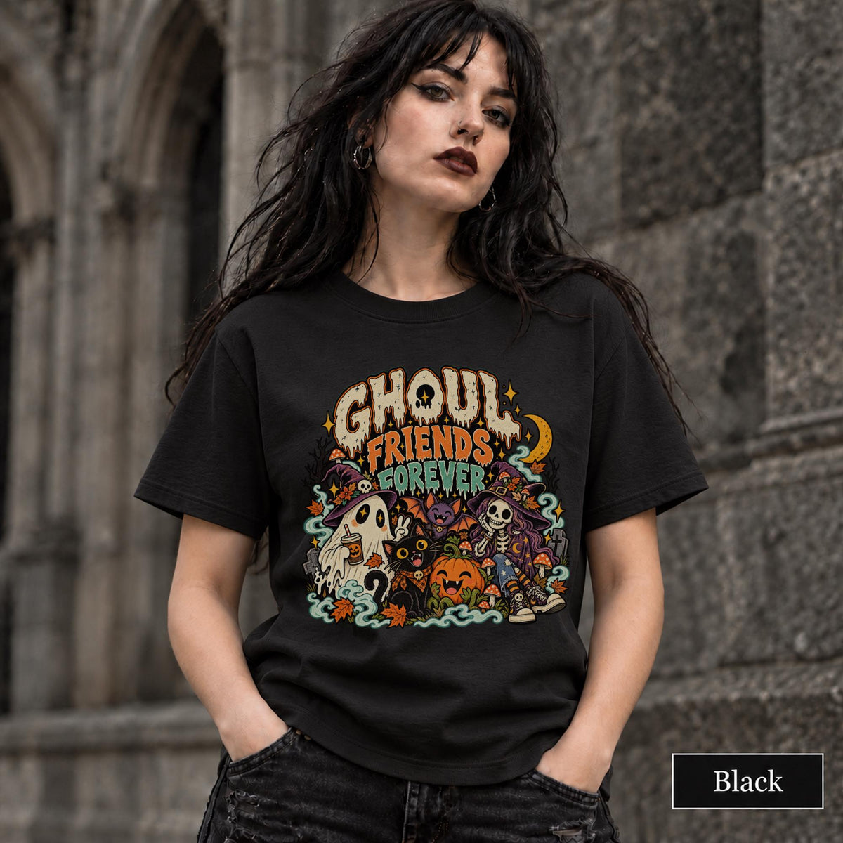 Black unisex T-shirt featuring a colorful “Ghoul Friends Forever” Halloween graphic with a ghost, black cat, pumpkin, witchy skeleton, bats, mushrooms, crescent moon, and autumn accents.
