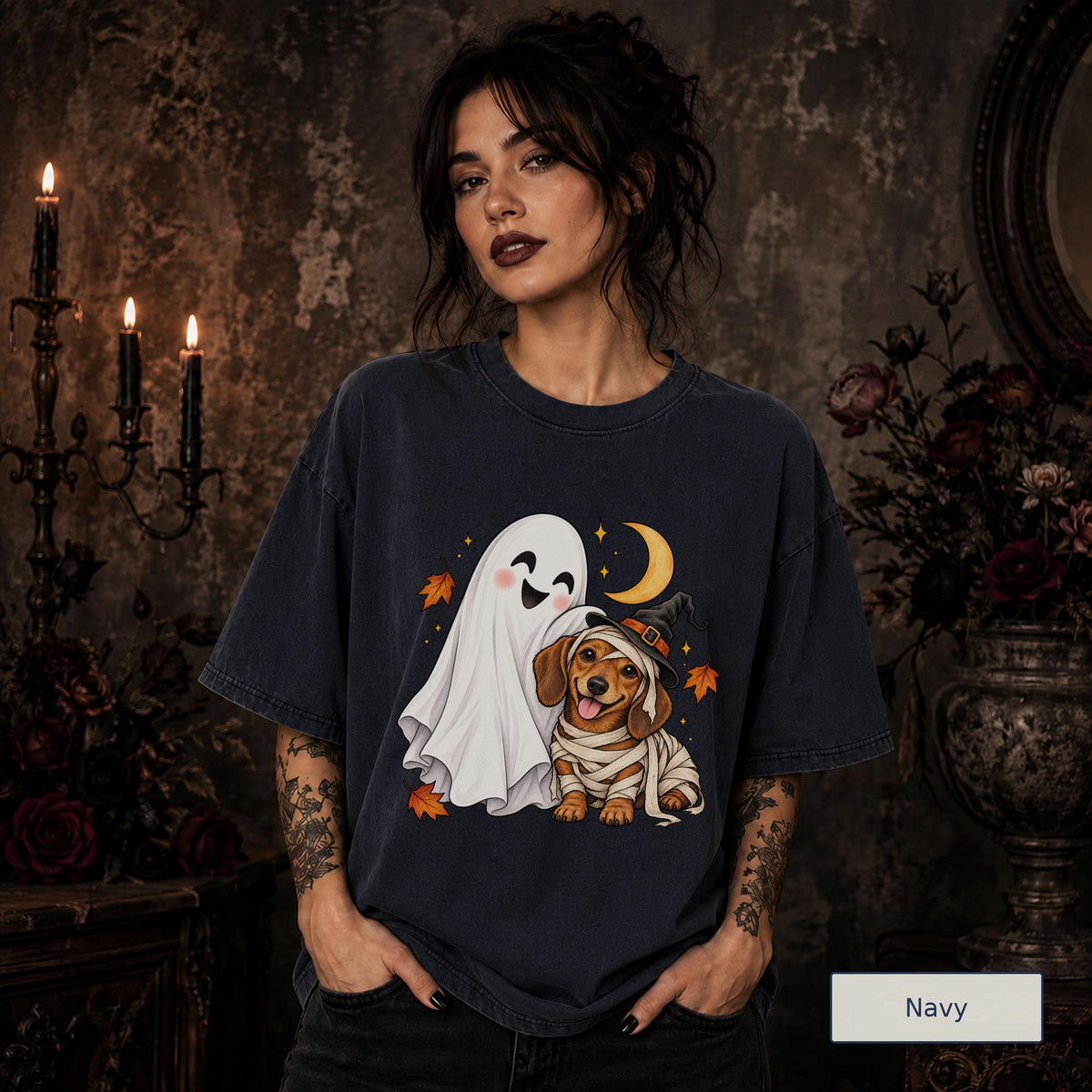 Navy unisex T-shirt featuring a smiling white ghost beside a mummy-wrapped puppy wearing a witch hat, with a crescent moon, stars, and orange autumn leaves.