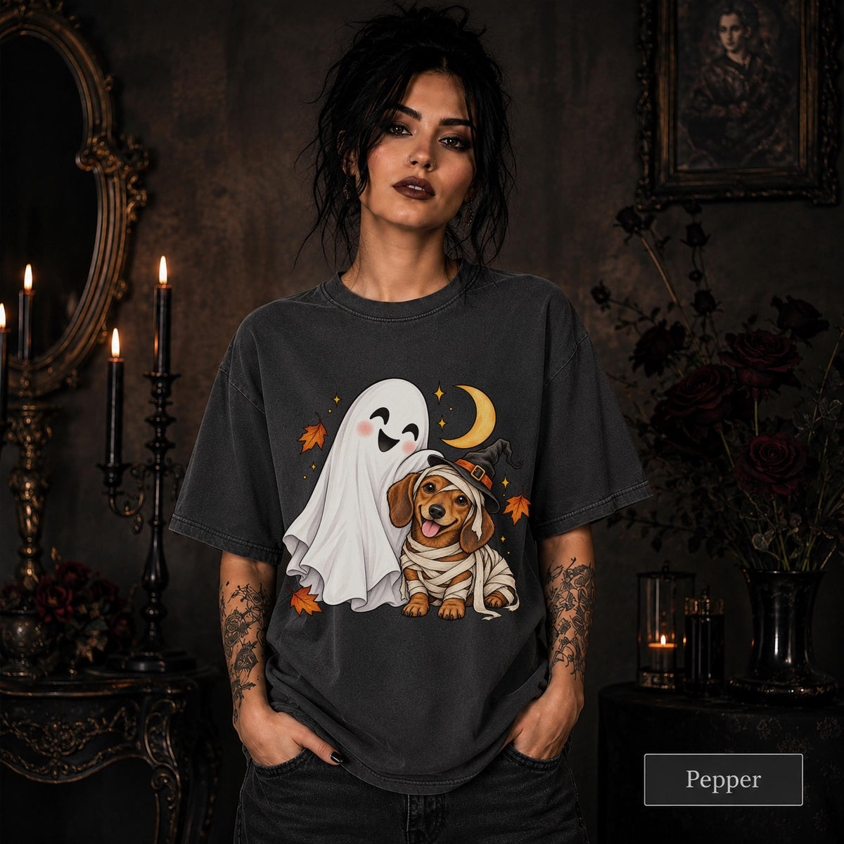 Pepper unisex T-shirt featuring a smiling white ghost beside a mummy-wrapped puppy wearing a witch hat, with a crescent moon, stars, and orange autumn leaves.