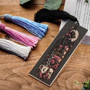 Gothic acrylic bookmark with pink, blue, white, black tassel featuring a sleeping black cat, celestial books, moon, pink flowers, coffee cup and skull.