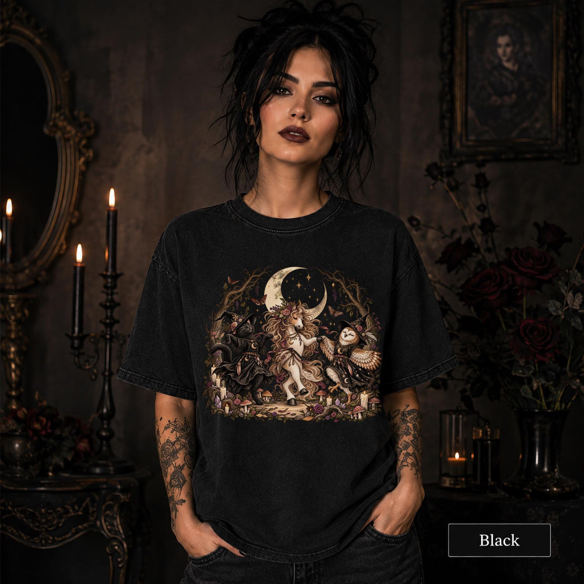 Black unisex T-shirt featuring a gothic fantasy scene with a unicorn, owls, raven, crescent moon, mushrooms, candles, flowers, and twisted woodland branches.