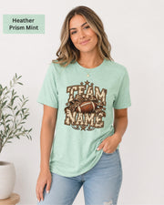 Heather Prism Mint Bella+Canvas 3001 unisex T-shirt featuring a customizable vintage football graphic with bold “Team Name” lettering, leopard-print bow, stars, and distressed varsity details.