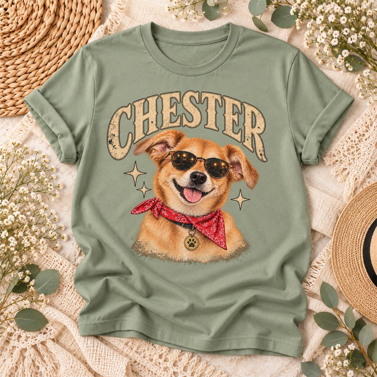 Sage green T-shirt displaying the custom Chester pet portrait artwork featuring a golden dog in sunglasses, a red bandana, distressed retro lettering and a vintage-inspired graphic style.