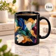 11 oz black ceramic mug shown from the opposite side, highlighting the colorful modern wrap design and bold artistic texture.