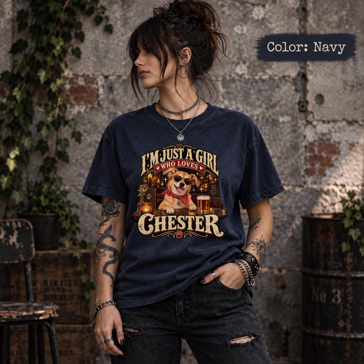 Woman modeling a navy custom pet portrait T-shirt with Chester's name, a golden dog wearing sunglasses and a red bandana, and warm vintage-inspired pub artwork.