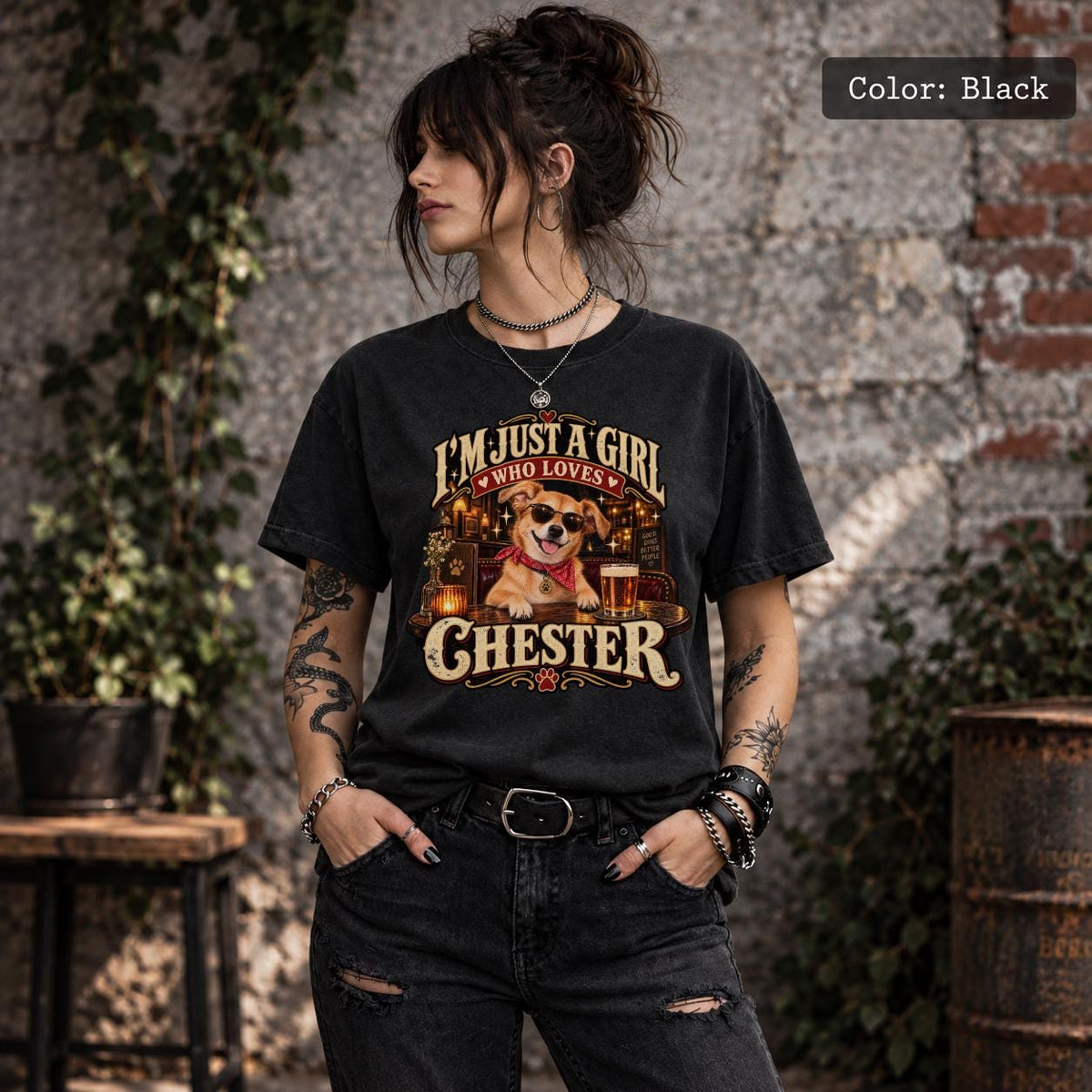 Woman wearing a black custom dog photo T-shirt showing Chester in sunglasses with a personalized name, warm amber lighting and vintage-inspired graphics.