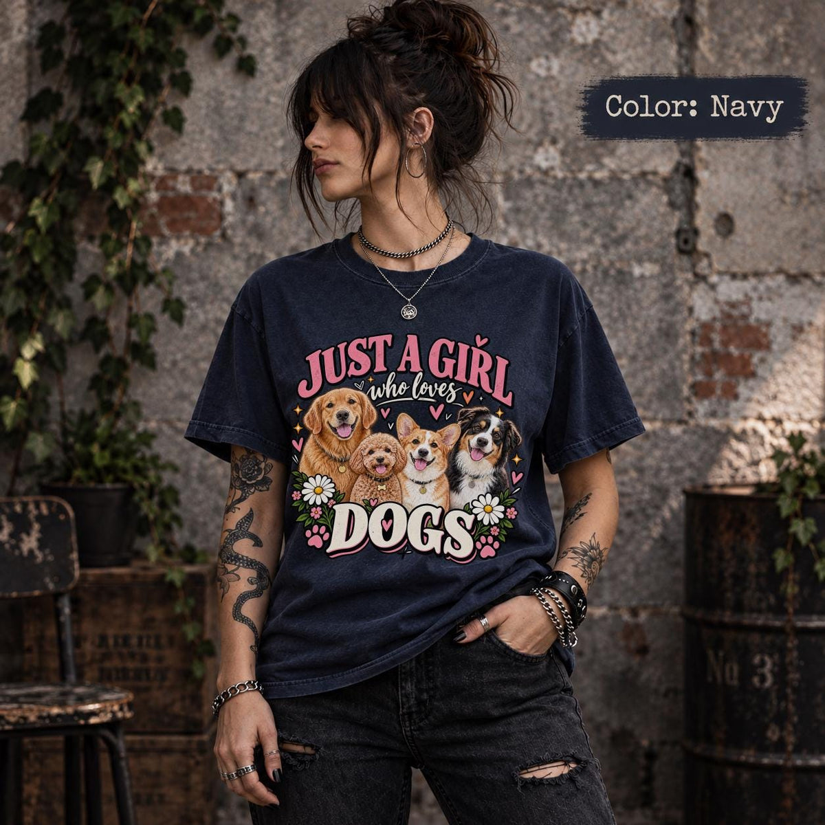 Woman wearing a navy blue dog mom graphic T-shirt featuring four adorable dog portraits, pink lettering, colorful flowers and decorative paw prints.
