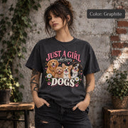 Lifestyle mockup of a woman wearing a graphite T-shirt displaying vintage-inspired Just a Girl Who Loves Dogs artwork with four dogs, pink hearts and floral accents.