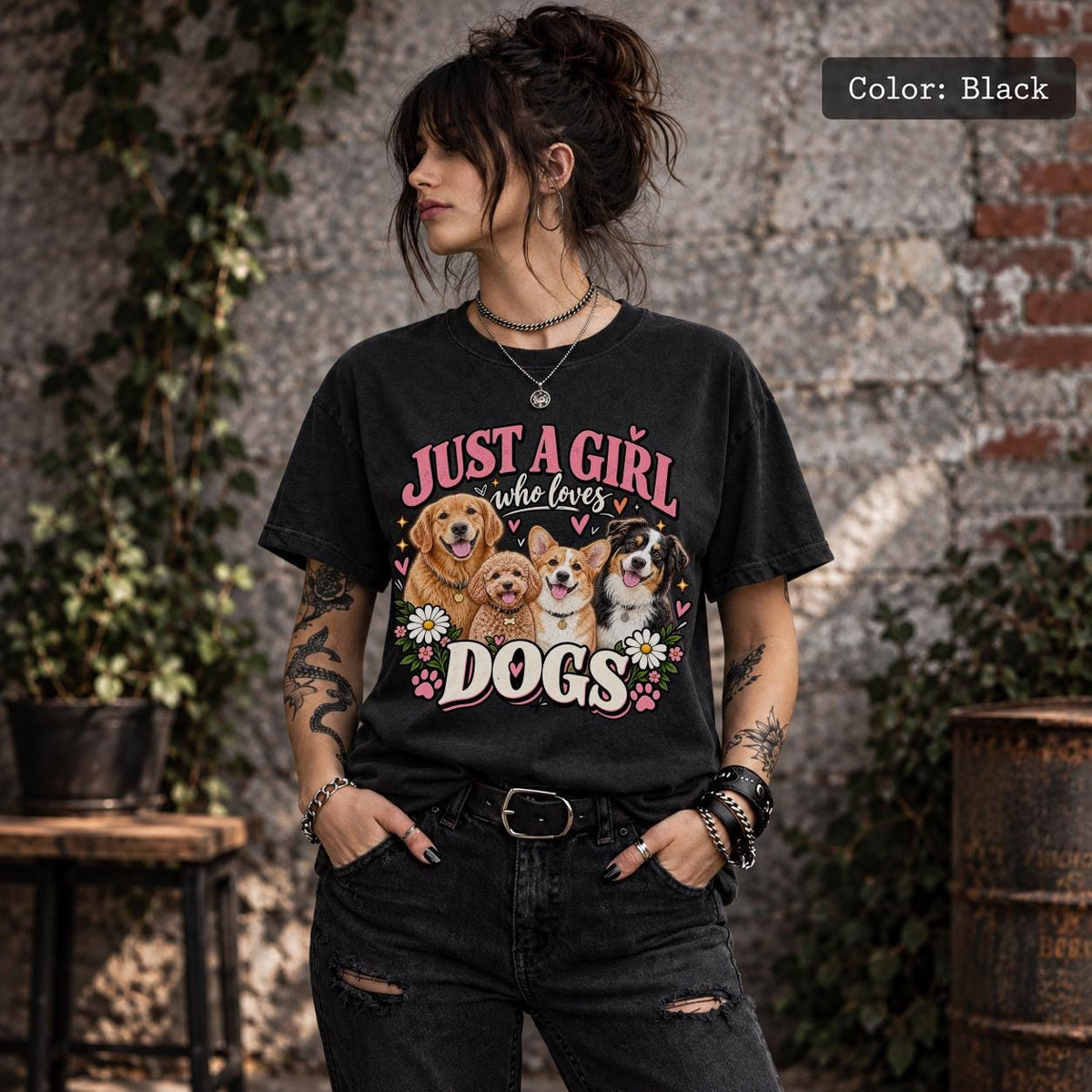 Lifestyle mockup of a woman wearing a black T-shirt displaying vintage-inspired Just a Girl Who Loves Dogs artwork with four dogs, pink hearts and floral accents.