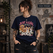 Lifestyle mockup of a woman wearing a Midnight T-shirt displaying vintage-inspired Just a Girl Who Loves Dogs artwork with four dogs, pink hearts and floral accents.