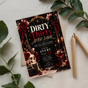 Dirty Thirty birthday party invitation displayed on a light surface surrounded by green tropical leaves and neutral accessories. Elegant black, burgundy, and gold cocktail-themed design for a 30th birthday celebration.