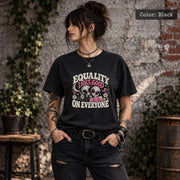 Color Black tee displaying the inclusive statement graphic with aliens, stars, hearts, flowers, and pink retro accents.