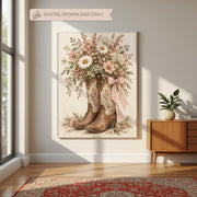 Country-inspired floral boot artwork displayed in a wooden frame on a cabinet beside a leafy houseplant. The soft pink bow, delicate blossoms, and weathered brown cowboy boots create a rustic feminine accent.