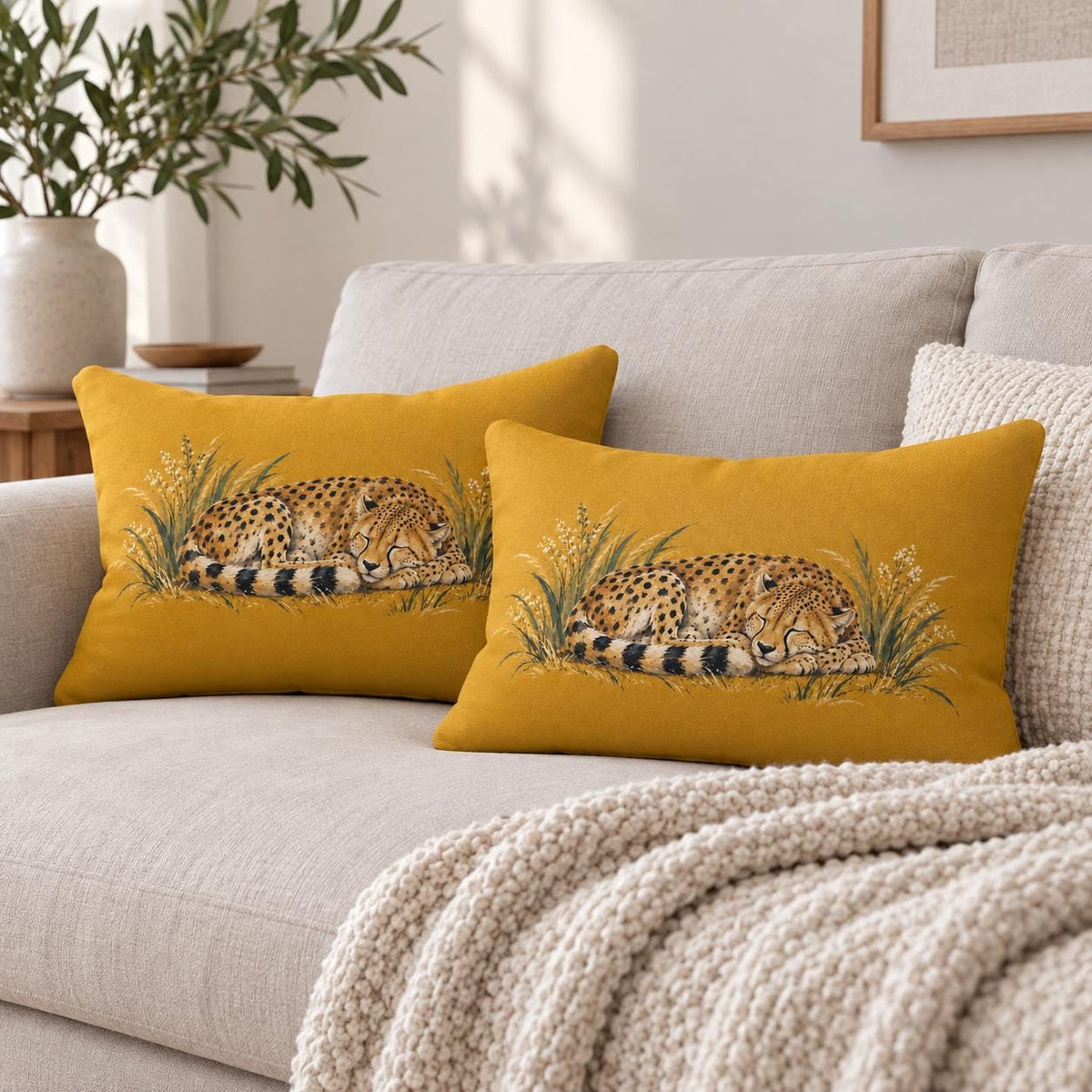wo matching mustard yellow sleeping cheetah lumbar pillows styled together on a cream sofa with cozy knit blanket and neutral home decor.