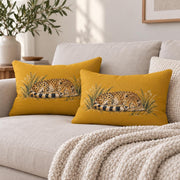 wo matching mustard yellow sleeping cheetah lumbar pillows styled together on a cream sofa with cozy knit blanket and neutral home decor.