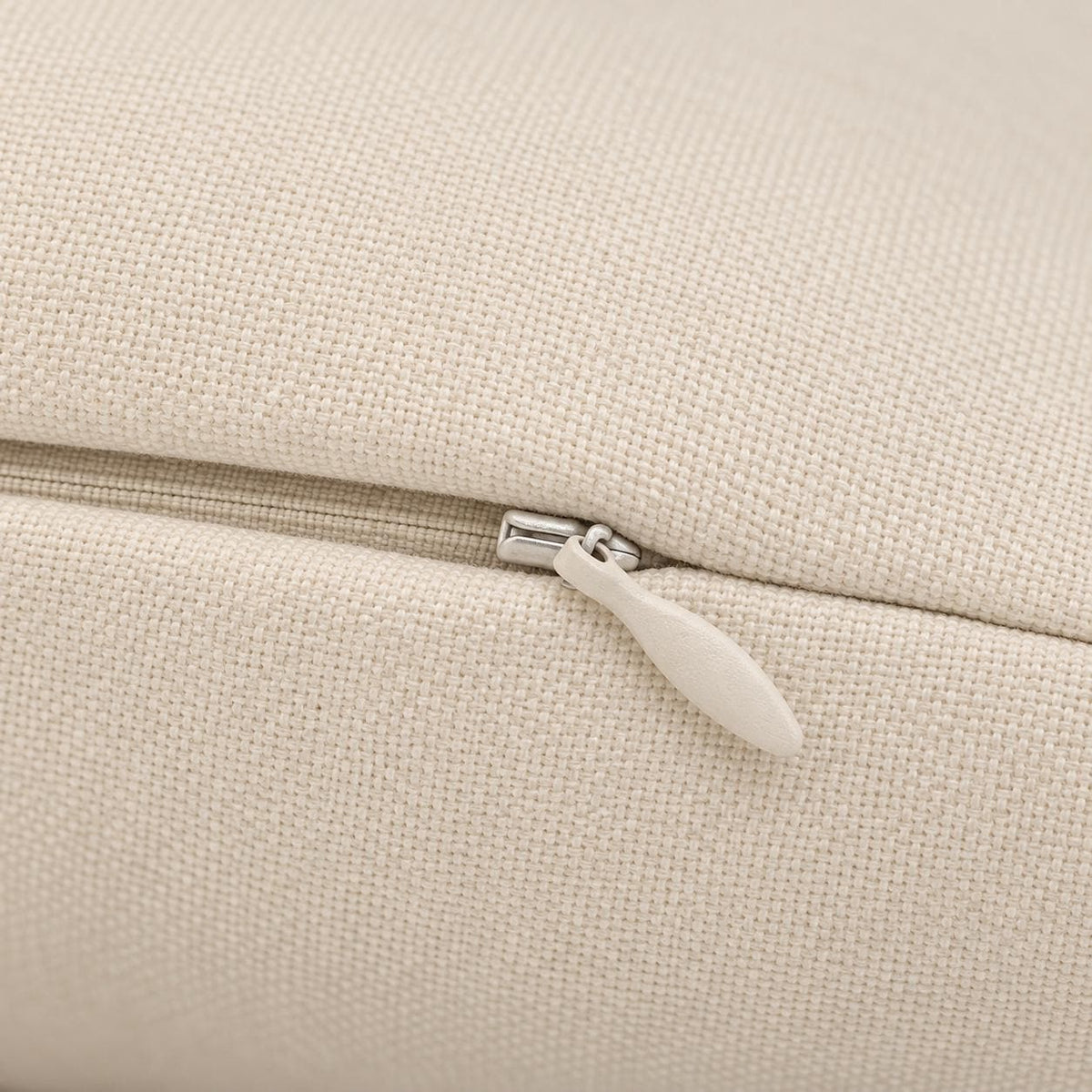 Close-up of cream Sawdust Soul pillow fabric showing the concealed beige zipper, metal zipper head, and textured polyester material.