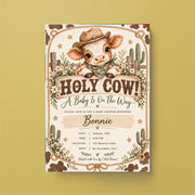 Editable cow baby shower invitation displayed on a warm golden-yellow background. The country-themed artwork features a smiling baby cow in a cowboy hat, delicate wildflowers, and soft brown and sage green colours.