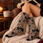 Woman relaxing in a cozy reading nook wearing gothic cat socks with black toes and heels. Warm candlelight, coffee, books, and a soft cream blanket create a cozy alternative fashion setting.