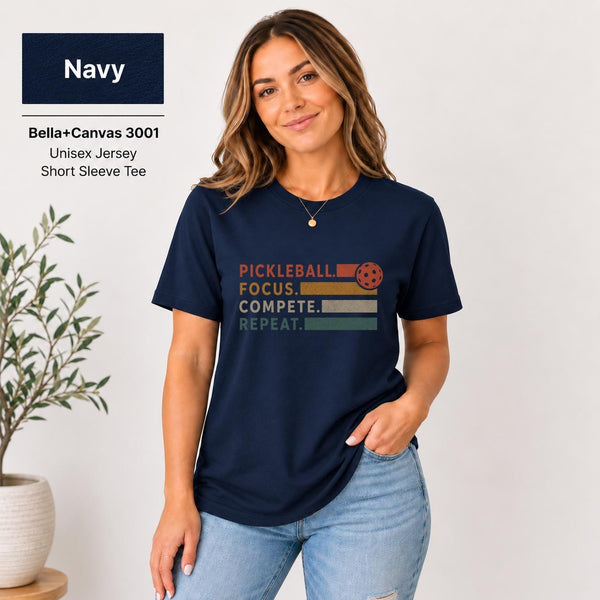 Navy Bella+Canvas unisex T-shirt featuring a minimalist statement graphic in warm orange and red lettering, modeled in a bright neutral setting.