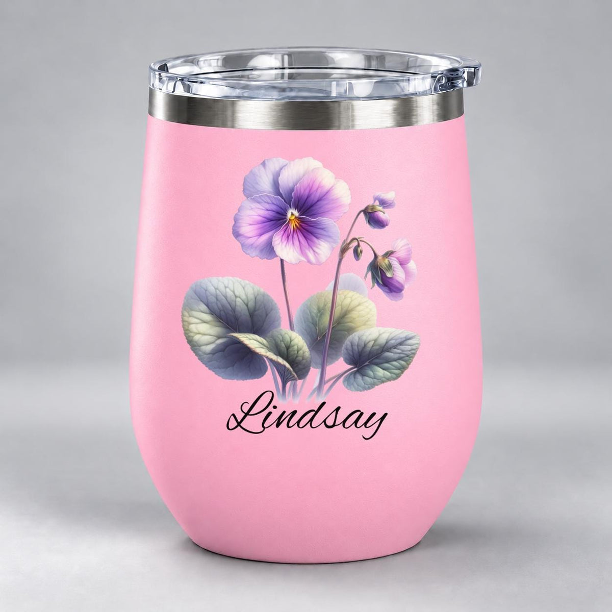 Pink 12oz wine tumbler displaying the personalized floral design with violet blossoms, green leaves, and script name.