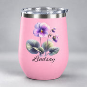 Pink 12oz wine tumbler displaying the personalized floral design with violet blossoms, green leaves, and script name.