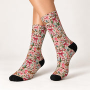 Side-angle product photo of pink bow cowgirl socks showing the full crew length and colorful western-inspired design. Features pink cowboy boots, green cacti, vintage floral motifs, horseshoes, and contrasting black heels and toes.