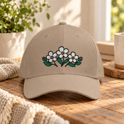 Khaki Flexfit hat showcasing the embroidered white floral design with green leaves on the front panel.