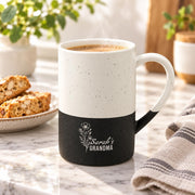 Black and cream 13oz ceramic mug featuring a delicate engraved floral design with personalized “Grandma” wording, styled beside books and neutral home decor.