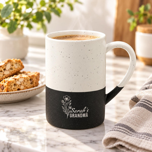 Black and cream 13oz ceramic mug featuring a delicate engraved floral design with personalized “Grandma” wording, styled beside books and neutral home decor.