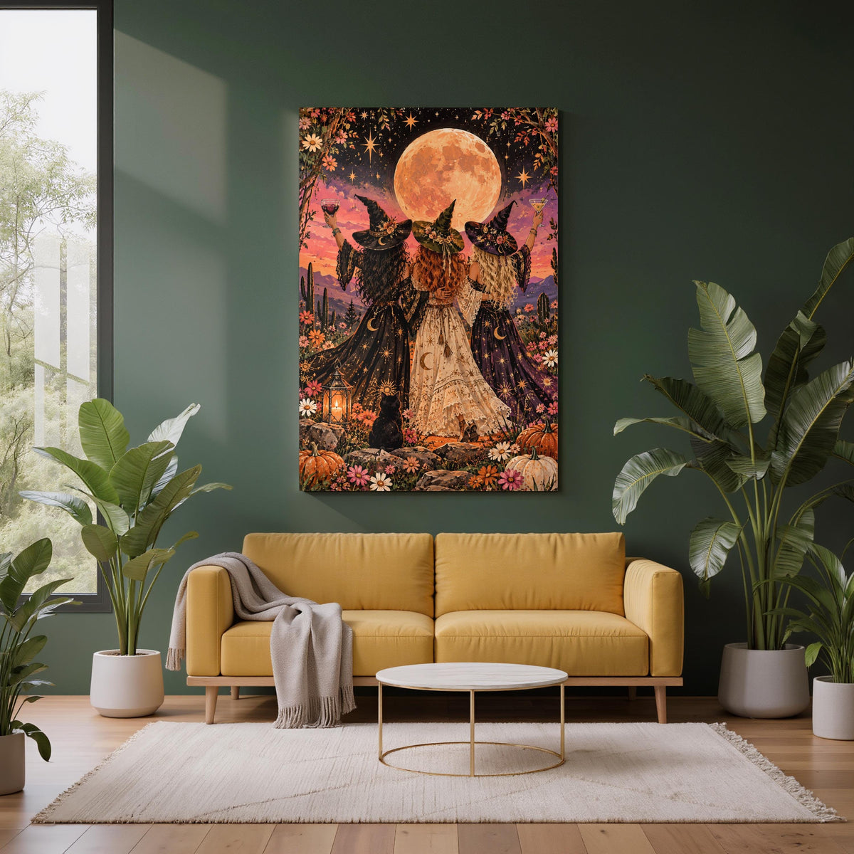 Framed celestial witch artwork displayed above a mustard sofa against a deep green wall. The fantasy print features three witches in flowing gowns, colourful wildflowers, pumpkins, and a glowing orange moon.