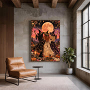 Moonlight, Magic & Mischief wall art displayed on a textured grey wall beside a tan leather chair. The mystical poster features three witches celebrating beneath a full moon with desert flowers and a black cat.