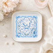 Personalized wedding ring dish styled with pearls, flowers, and ribbon, featuring custom initials S and J in a blue floral design.