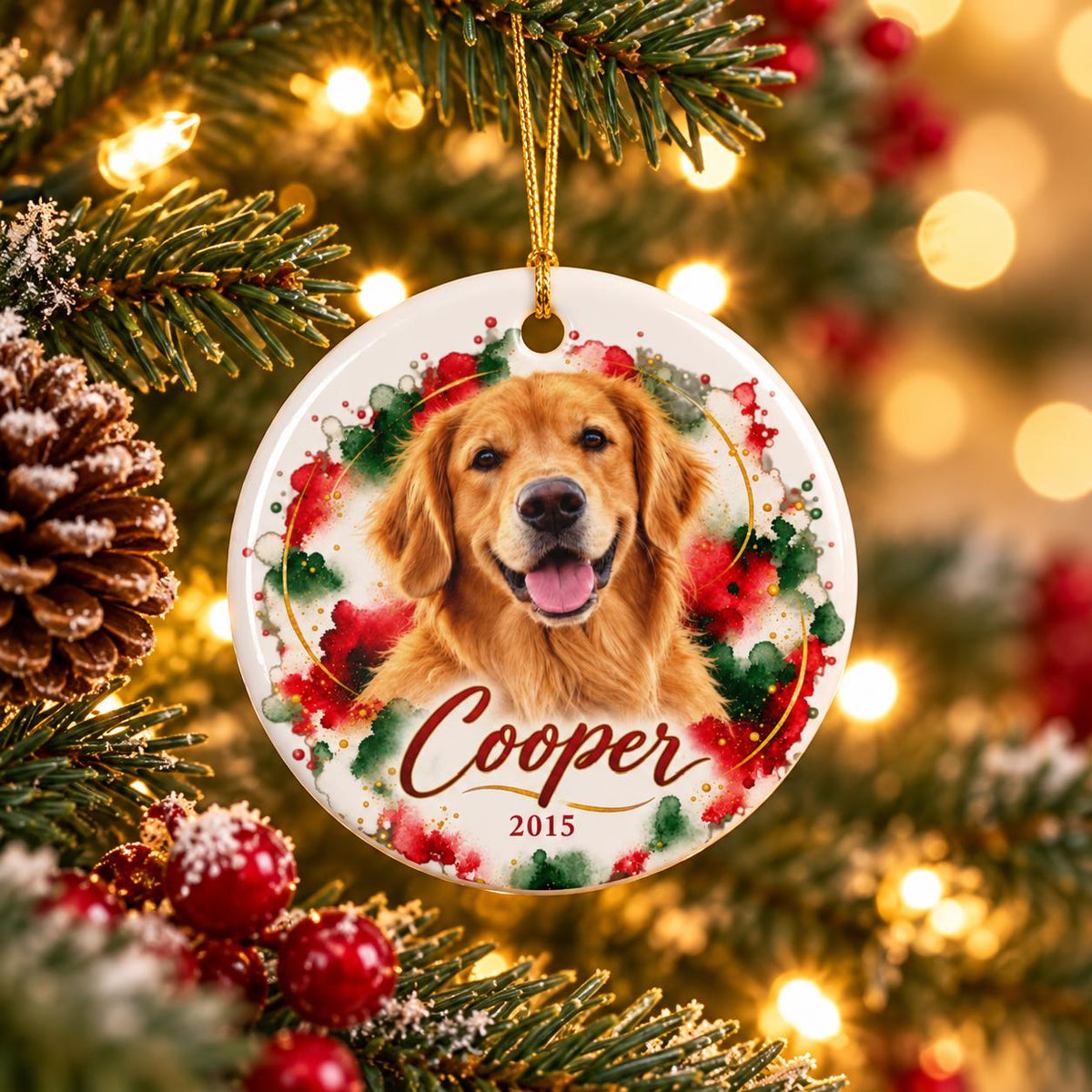 Personalized ceramic pet ornament hanging on a festive Christmas tree, featuring a golden retriever portrait, red, white, and green watercolor background, gold accents, Cooper's name, and the year 2015.
