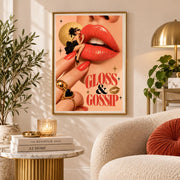 Sassy beauty wall art displayed above a cream boucle chair beside a wooden side table and leafy greenery. The framed Gloss and Gossip poster features dramatic red lips, a stylish woman wearing sunglasses, and vintage-inspired gold details.