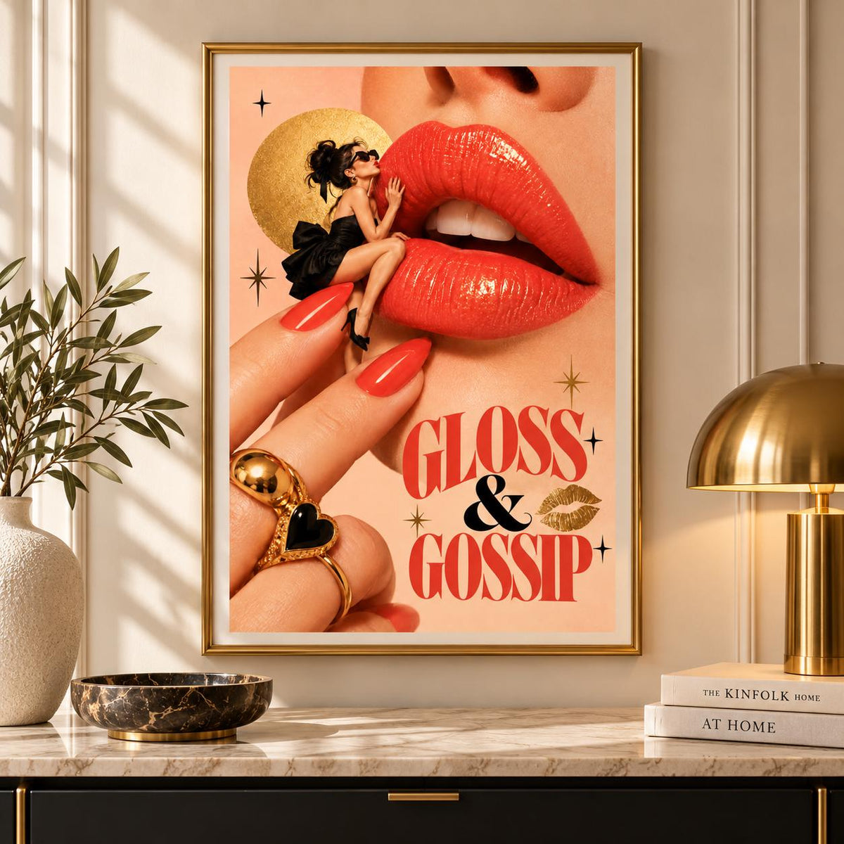 Gloss and Gossip printable poster displayed in a slim gold frame above a dark marble console. The vintage-inspired lipstick artwork features coral-red lips, luxurious gold rings, a miniature fashionista, and bold typography against a warm peach background.