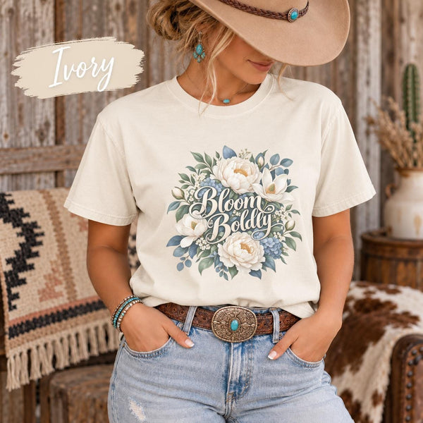 Ivory Comfort Colors T-shirt featuring a soft blue and cream floral graphic with delicate botanical details in a relaxed Western-style setting.