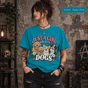 Woman modeling a Topaz blue graphic T-shirt featuring Just a Girl Who Loves Dogs design with four illustrated pups, pink and cream typography, hearts, daisies and paw prints.