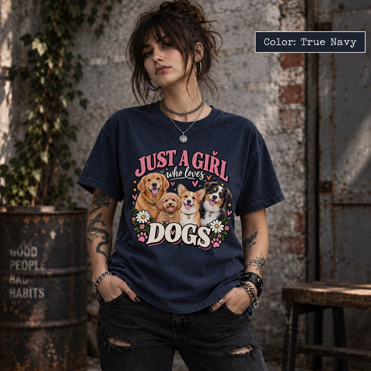 Woman wearing a true navy blue dog mom graphic T-shirt featuring four adorable dog portraits, pink lettering, colorful flowers and decorative paw prints.