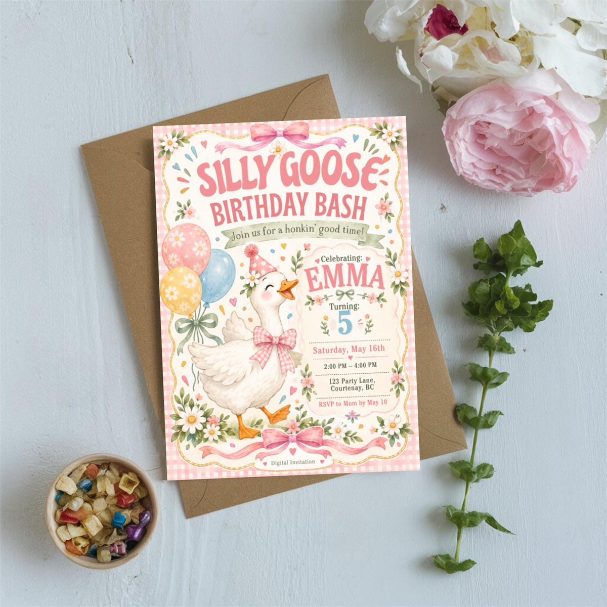 Silly Goose Birthday Bash invitation styled on a light tabletop with soft flowers and decorative accents, showing the pink watercolor birthday design and customizable celebration details.