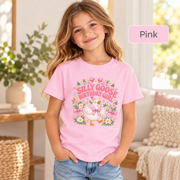 Young girl wearing a pink Silly Goose Birthday Girl T-shirt featuring a cheerful white goose in a party hat, pink gingham bows, pastel flowers and playful birthday lettering.