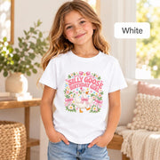 Girl modeling a white birthday T-shirt featuring a cute goose in a pink party hat and gingham bow, surrounded by pastel daisies, hearts and playful pink lettering.