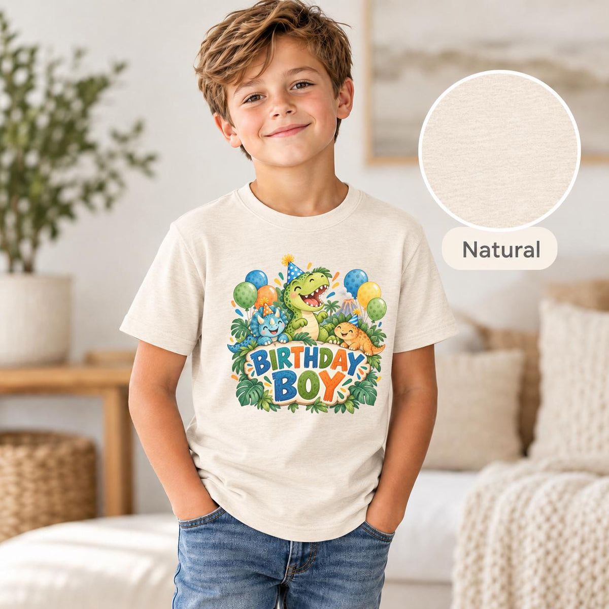 Boy wearing a natural cream dinosaur birthday tee featuring a colorful prehistoric party design with three adorable dinosaurs, tropical greenery and bold Birthday Boy text.