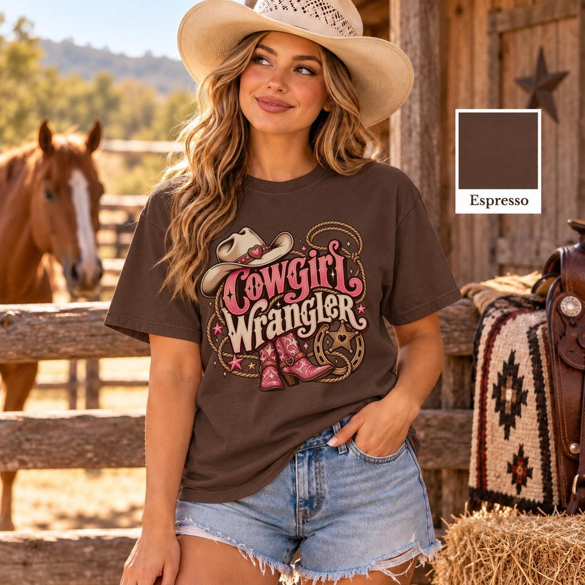 Cowgirl modeling a dark espresso Comfort Colors T-shirt with retro Cowgirl Wrangler design, featuring decorative pink lettering, cowboy hat, boots and rope illustrations.