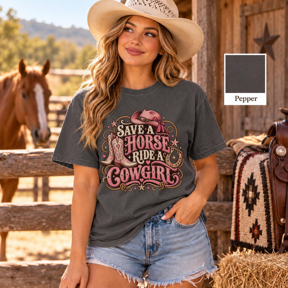 Blonde model wearing a pepper gray Save a horse ride a cowgirl T-shirt featuring pink Western typography, cowboy boots, rope details and a horseshoe, paired with casual denim shorts.