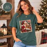 Blue Spruce Comfort Colors tee showing the custom pet Christmas design with Santa, evergreen trees, festive greenery, and a nostalgic postage-stamp border.