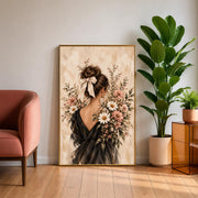 Framed feminine vintage wall art resting on a wooden cabinet beside a leafy green plant. A brunette woman surrounded by blush and ivory blossoms adds romantic charm to the neutral interior.