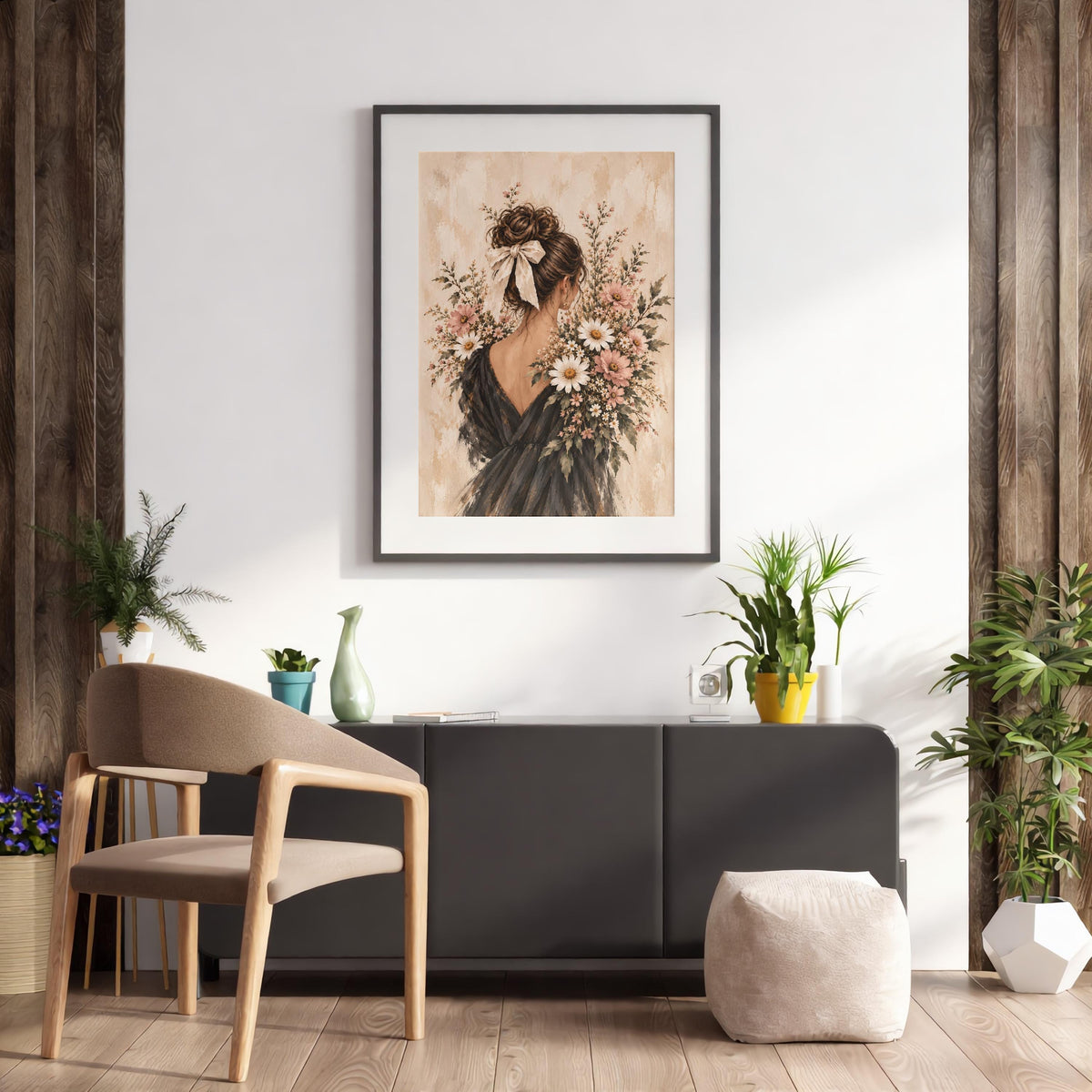 Framed coquette woman wall art displayed above a wooden desk and chair in a bright home office. The illustration features a brunette woman with a large ivory hair bow and flowing black gown.