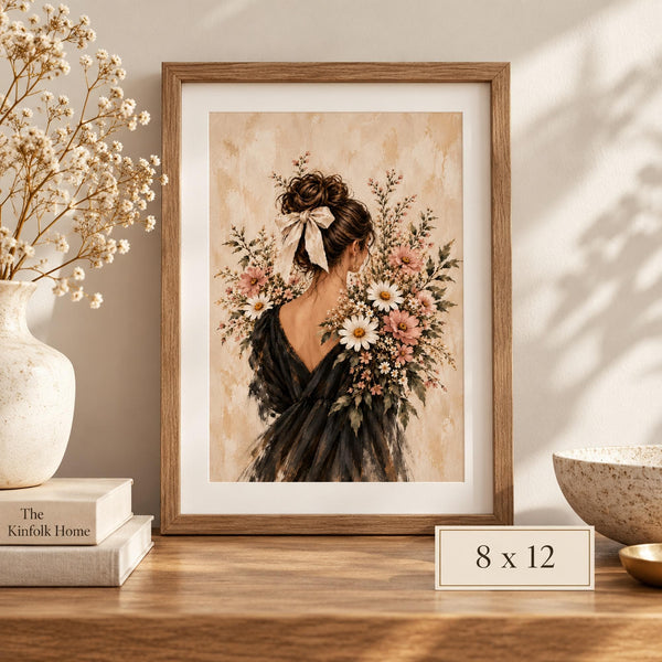 8 x 12 inch romantic floral portrait displayed in a wooden frame on a light console table with neutral home accessories. The museum-grade matte poster features a woman viewed from behind wearing a black dress and ivory bow, surrounded by pink and white botanical flowers.