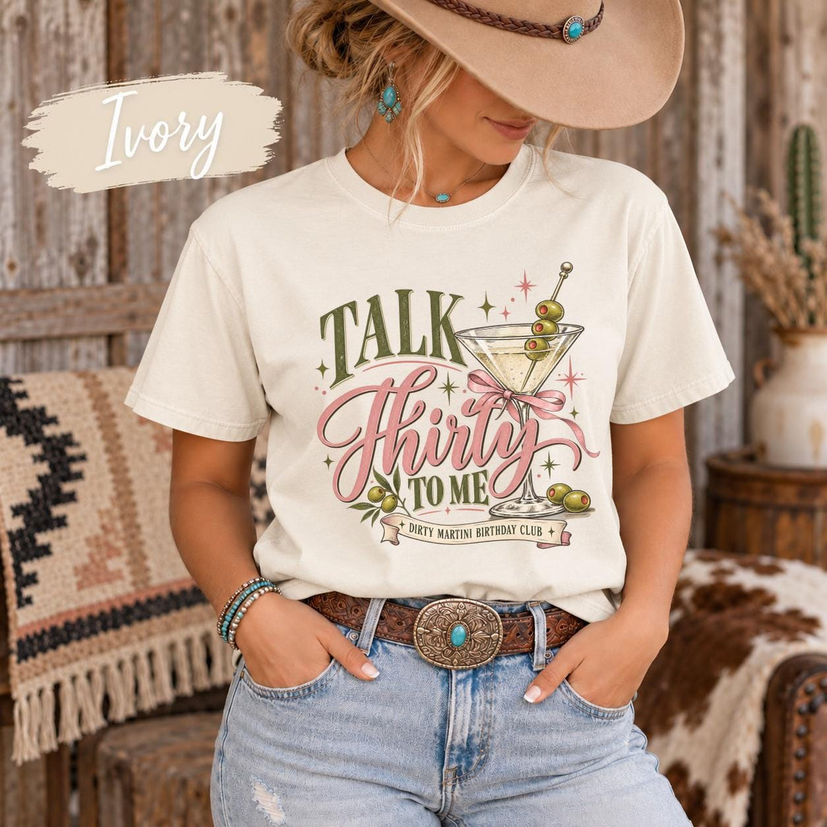 Ivory T-shirt featuring the “Talk Thirty to Me” dirty martini birthday design with pink script, olive green lettering, martini glasses, bows, and retro star accents.